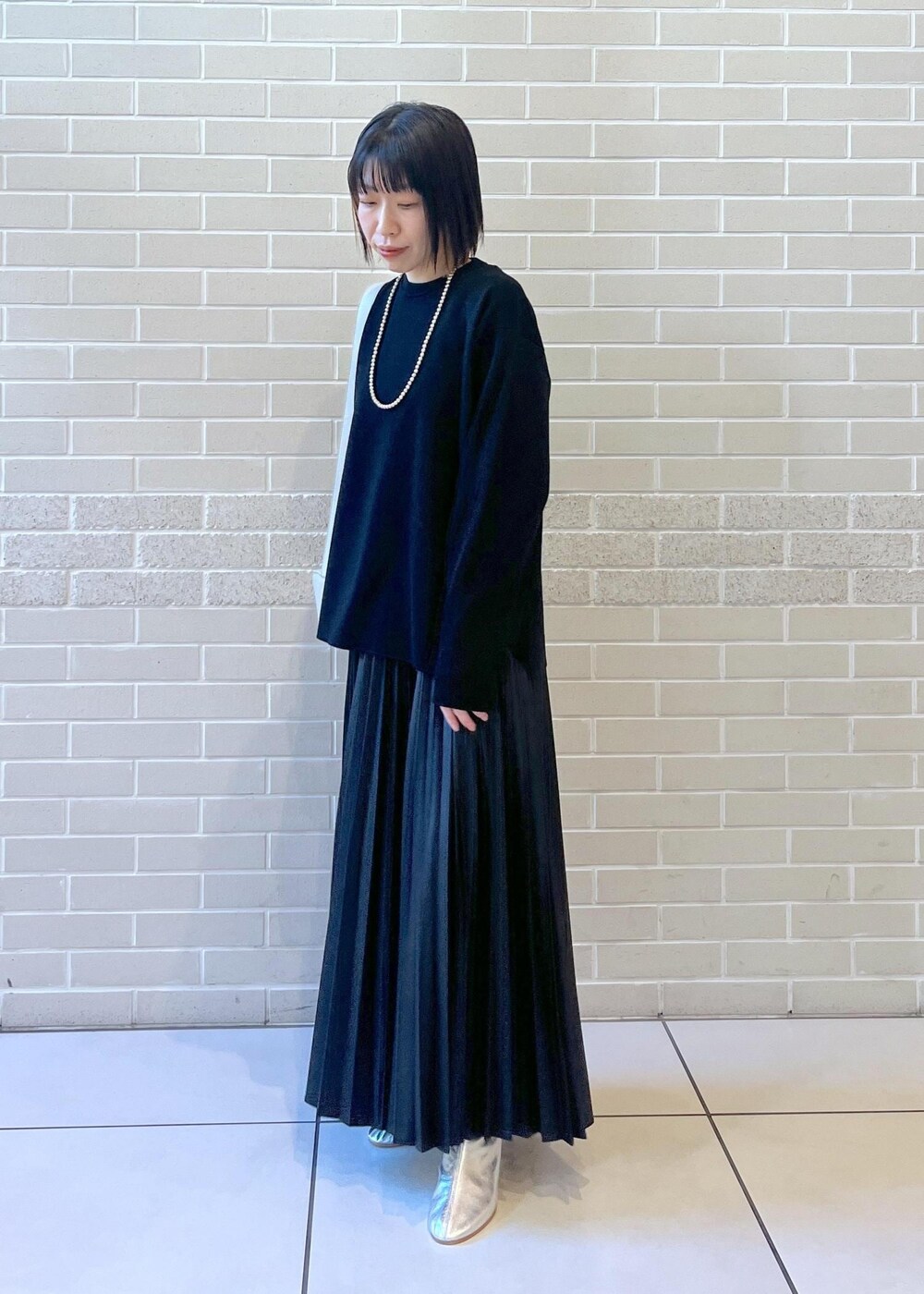 ブラック系のスカート、グレー系のショルダーバッグ、シルバー系のブーツを着用したレディースの秋コーディネートの3枚目の写真