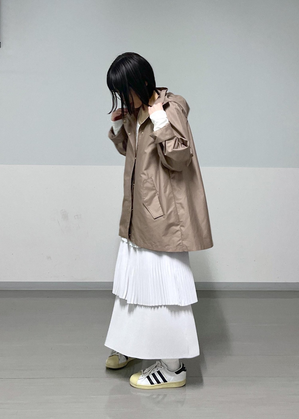 ブラウン系のマウンテンパーカー、グレー系のスカート、ブルー系のデニムパンツを着用したレディースの冬コーディネートの2枚目の写真