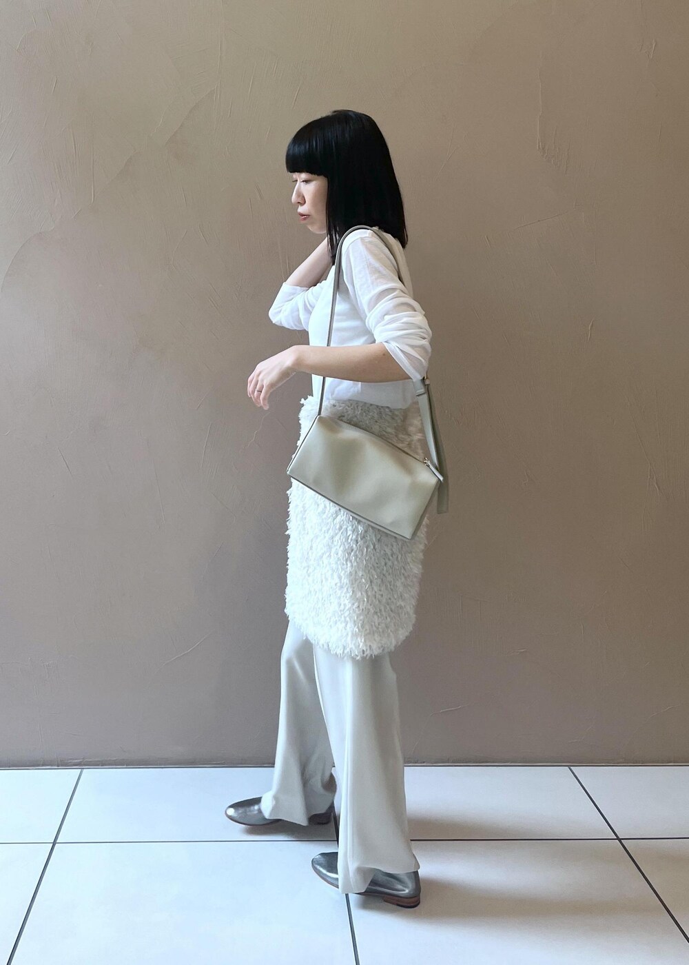 グレー系のショルダーバッグ、ホワイト系のスカート、ベージュ系のその他パンツを着用したレディースの秋コーディネートの2枚目の写真