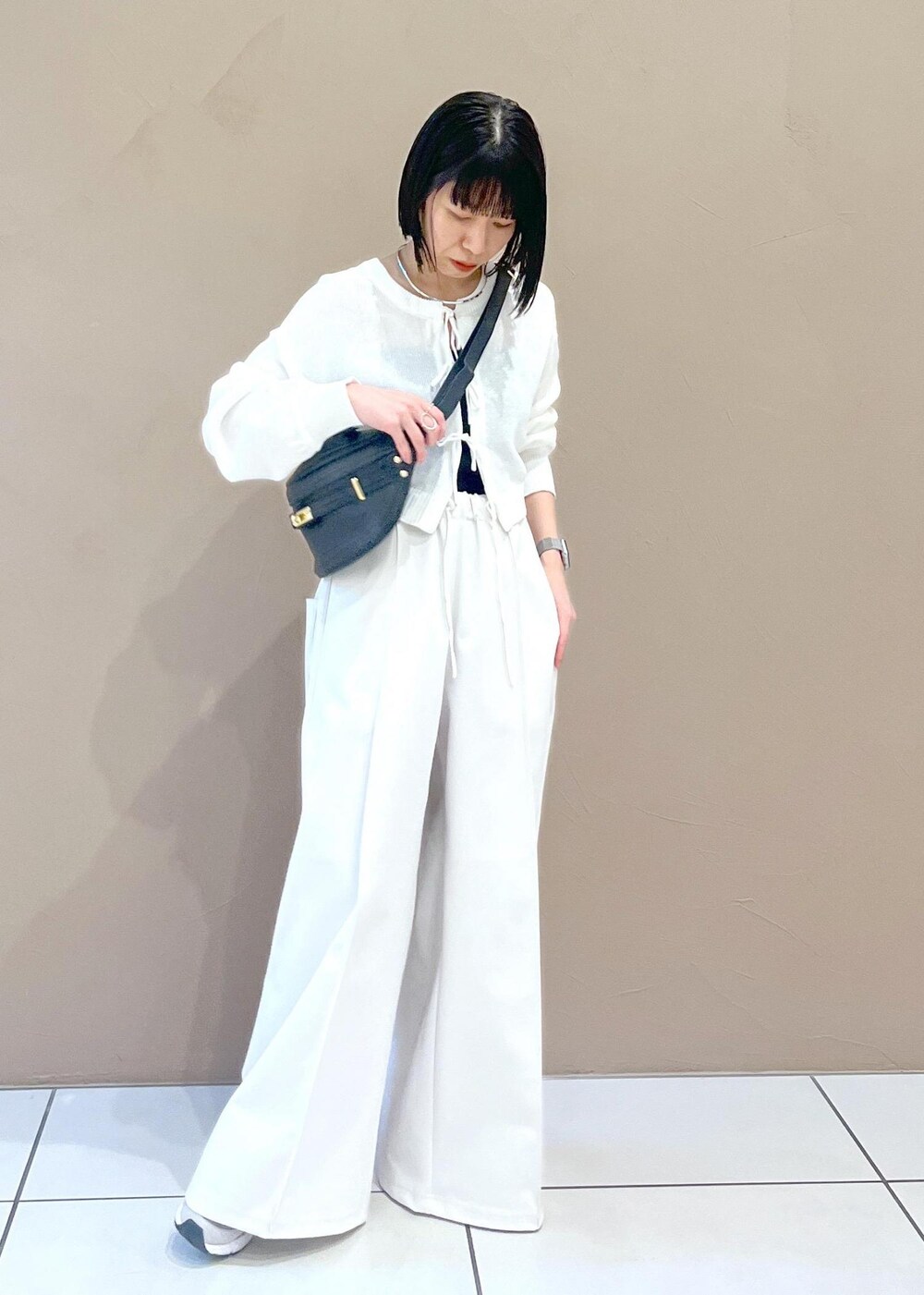 ホワイト系のニット/セーター、ブラック系のボディバッグ/ウエストポーチを着用したレディースの春コーディネートの2枚目の写真