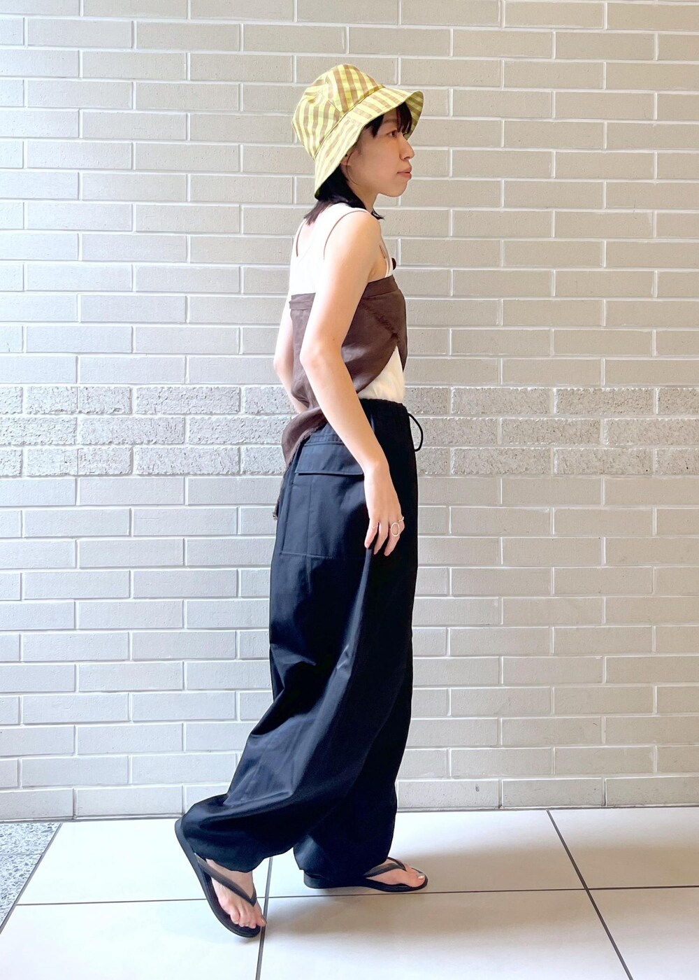 ホワイト系のタンクトップ、ブラック系のサンダル、ブラック系のカーゴパンツを着用したレディースの夏コーディネートの2枚目の写真