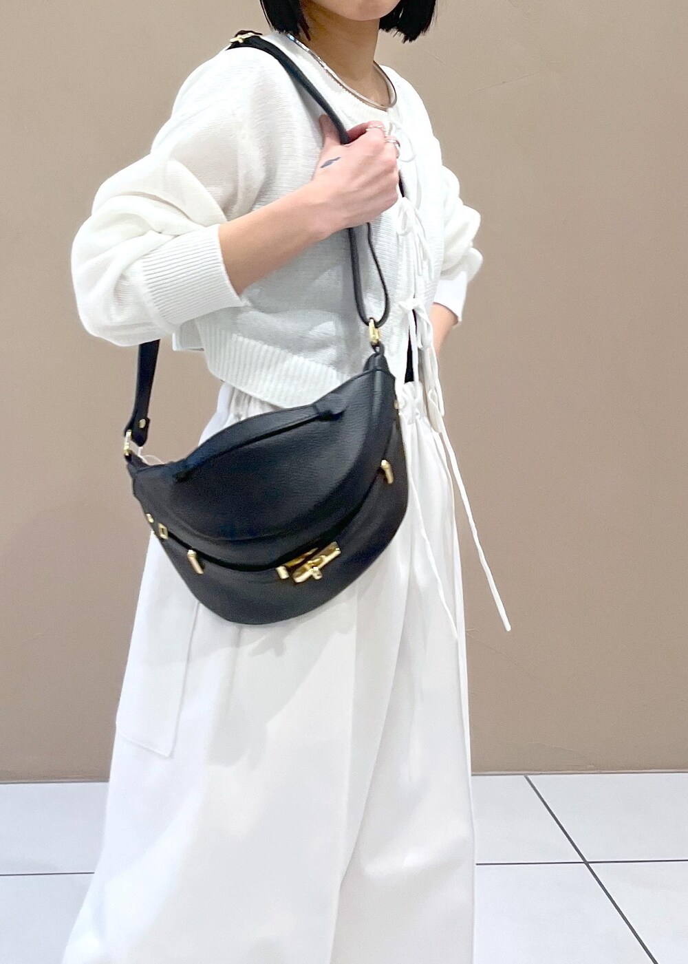 ホワイト系のニット/セーター、ブラック系のボディバッグ/ウエストポーチを着用したレディースの春コーディネートの6枚目の写真