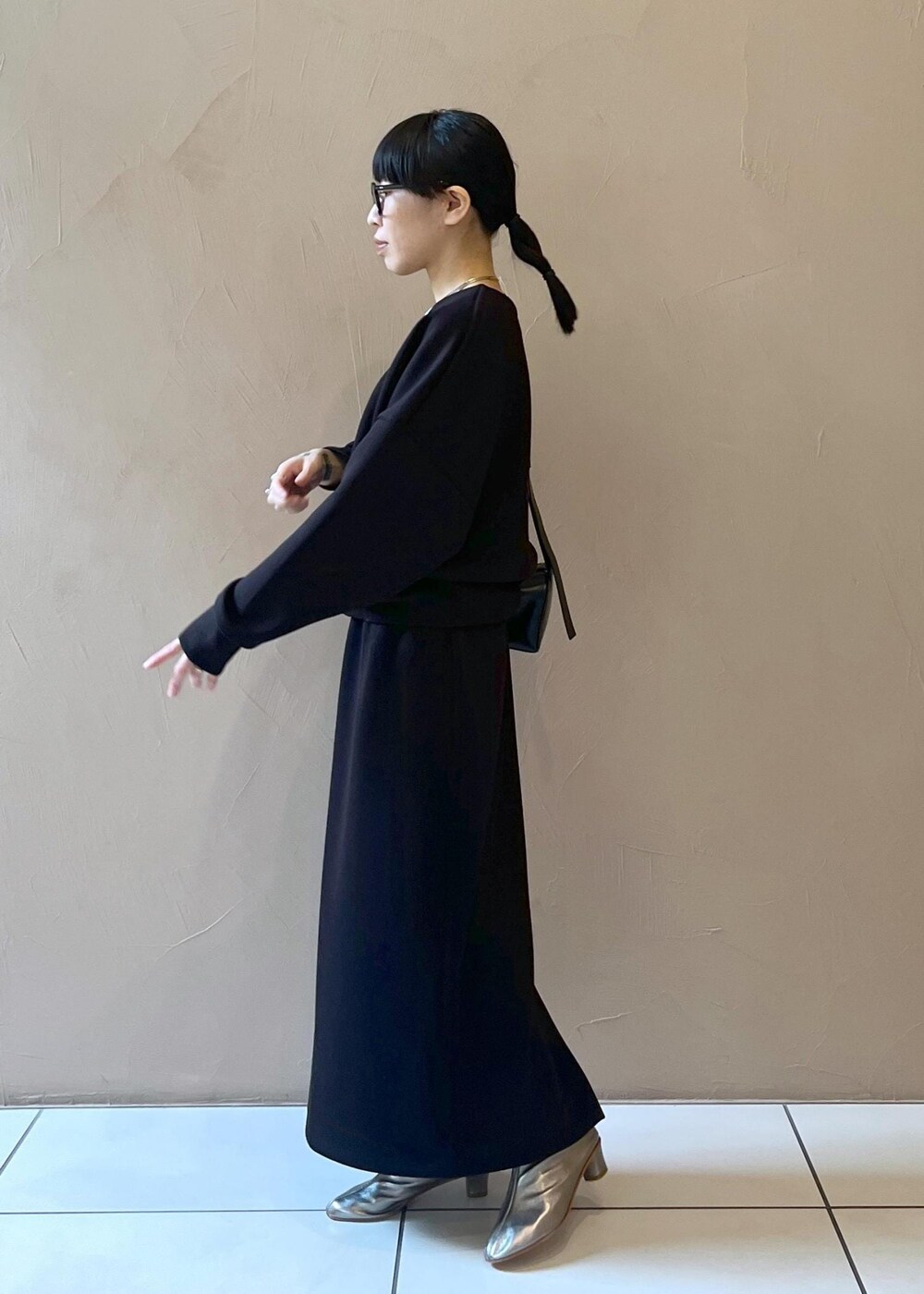 ブラック系のショルダーバッグ、ブラック系のスカート、ブラック系のTシャツ/カットソーを着用したレディースの秋コーディネートの2枚目の写真