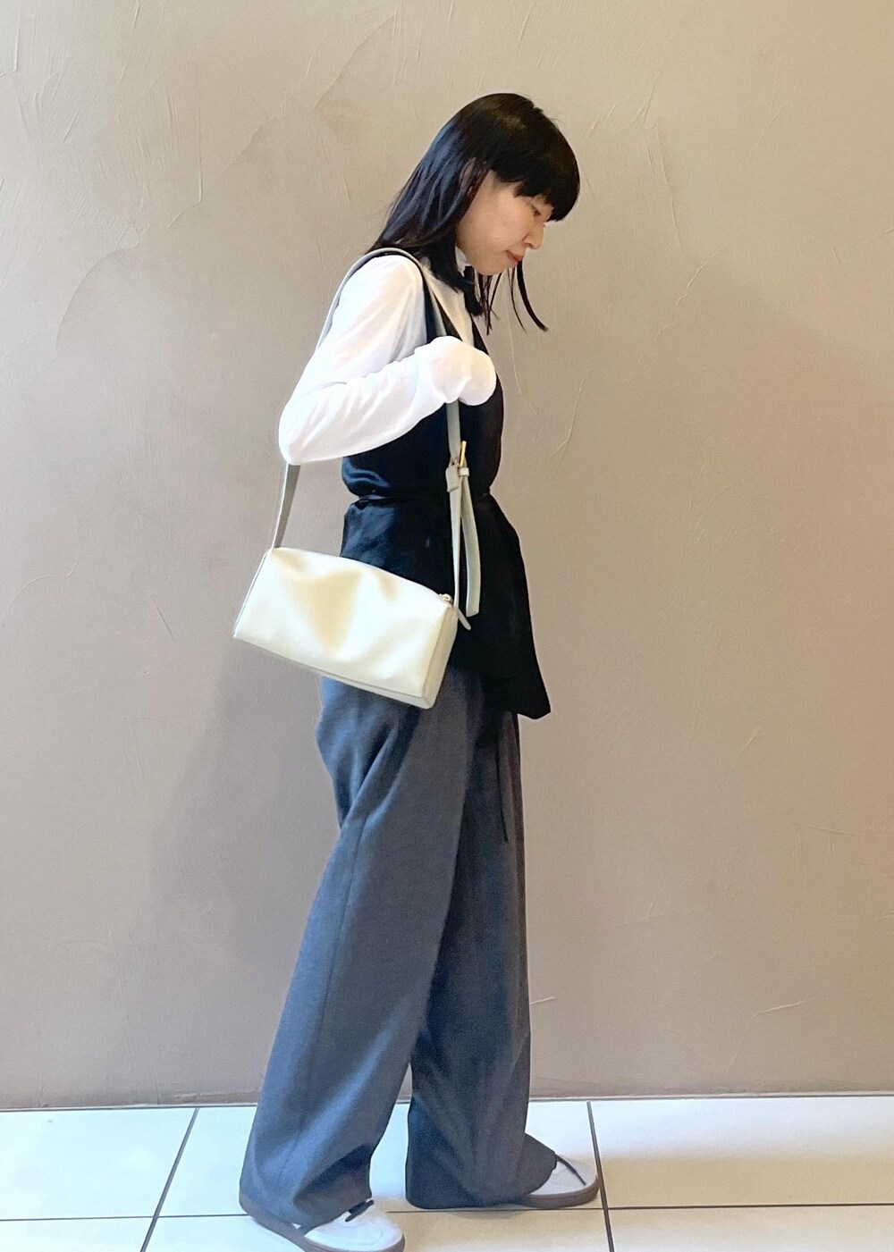 グレー系のショルダーバッグ、ブラック系のTシャツ/カットソー、グレー系のスラックスを着用したレディースの秋コーディネートの4枚目の写真