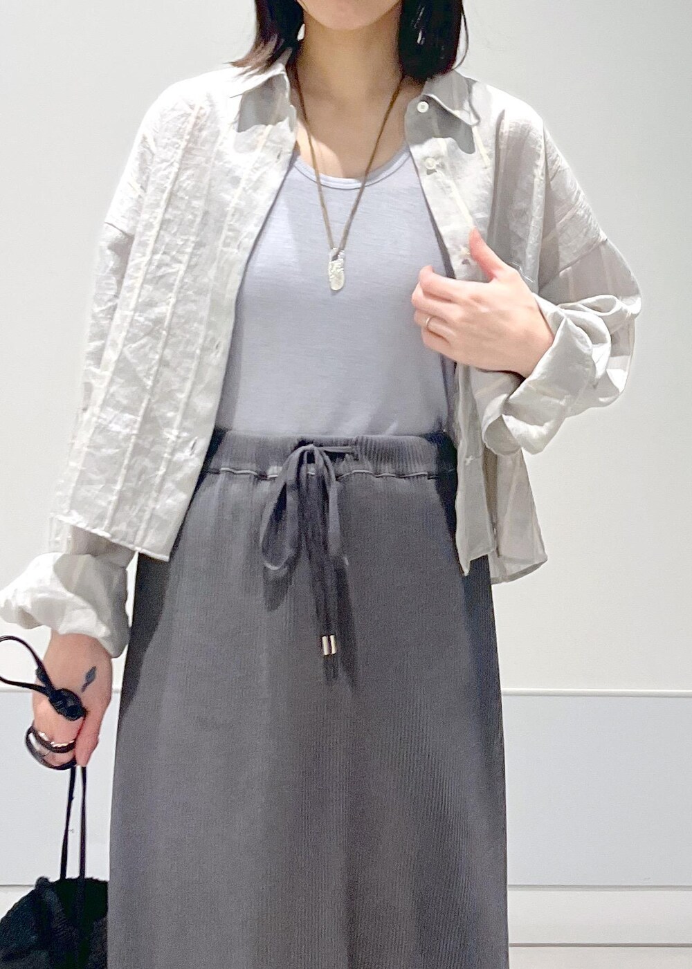 ブラック系のショルダーバッグ、グレー系のスカート、グレー系のタンクトップを着用したレディースの夏コーディネートの4枚目の写真