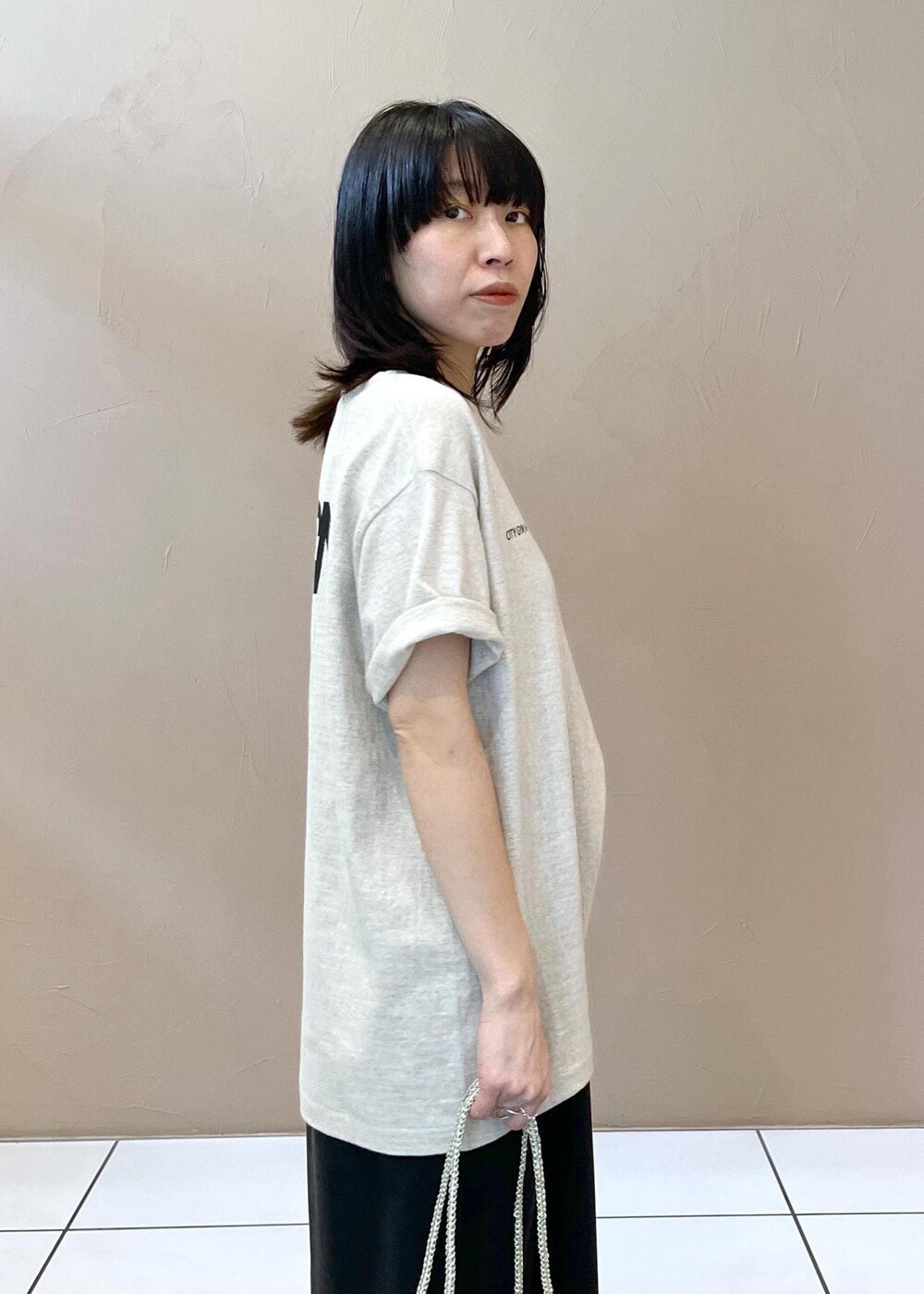 ブラック系のワンピース、ホワイト系のTシャツ/カットソー、シルバー系のトートバッグを着用したレディースの春コーディネートの6枚目の写真