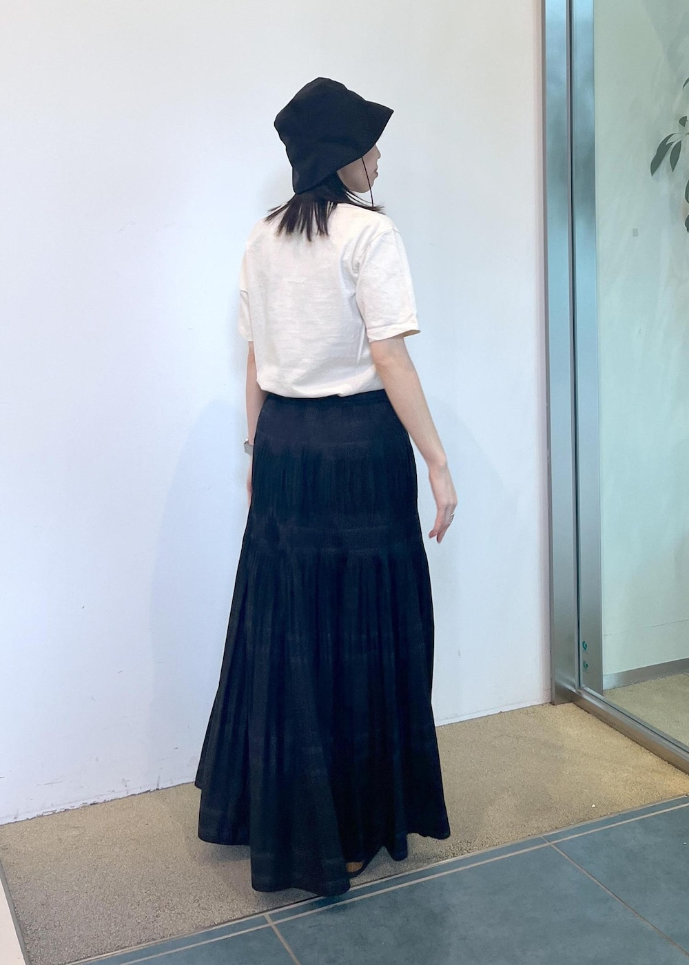 ブラック系のサンダル、ホワイト系のTシャツ/カットソー、ブラック系のスカートを着用したレディースの夏コーディネートの2枚目の写真