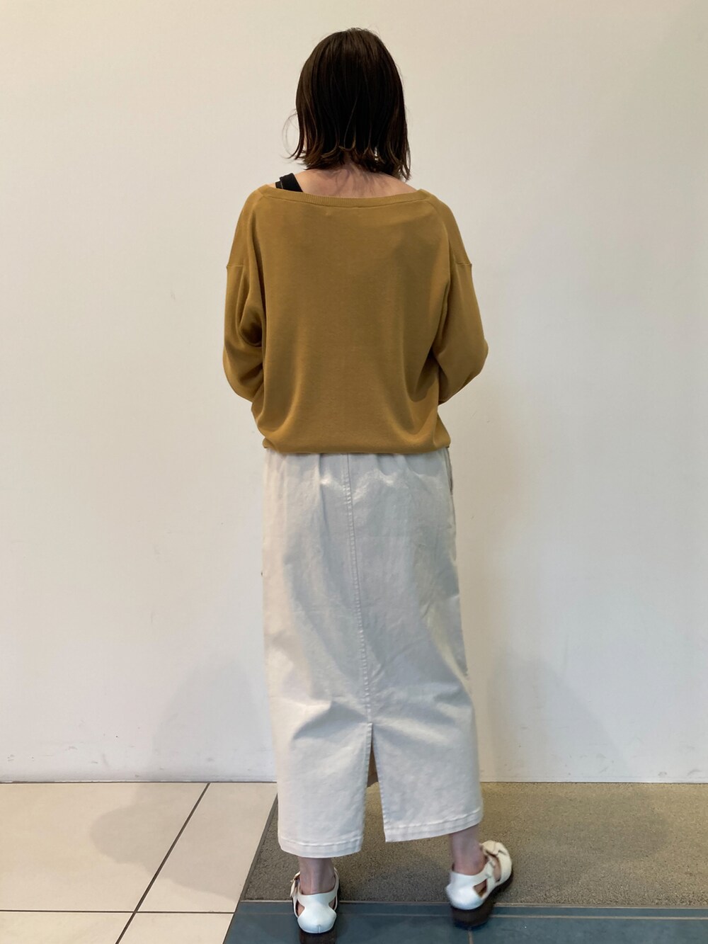 イエロー系のカーディガン/ボレロ、ベージュ系のかごバッグ、ホワイト系のスカートを着用したレディースの春コーディネートの3枚目の写真