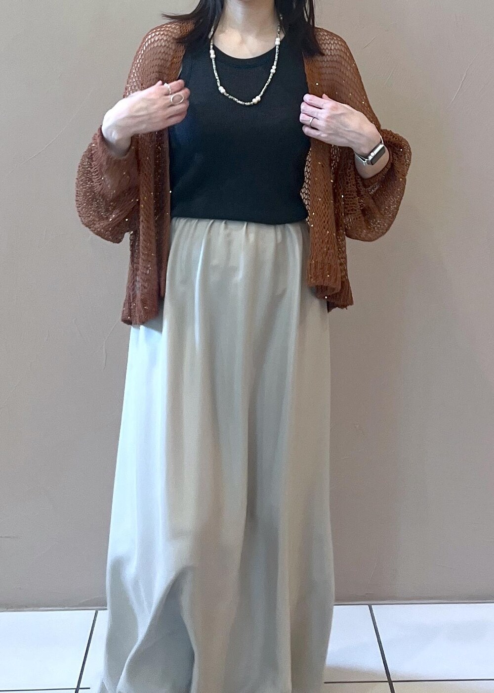 グレー系のタンクトップ、ブラウン系のカーディガン/ボレロ、ベージュ系のスカートを着用したレディースの夏コーディネートの5枚目の写真