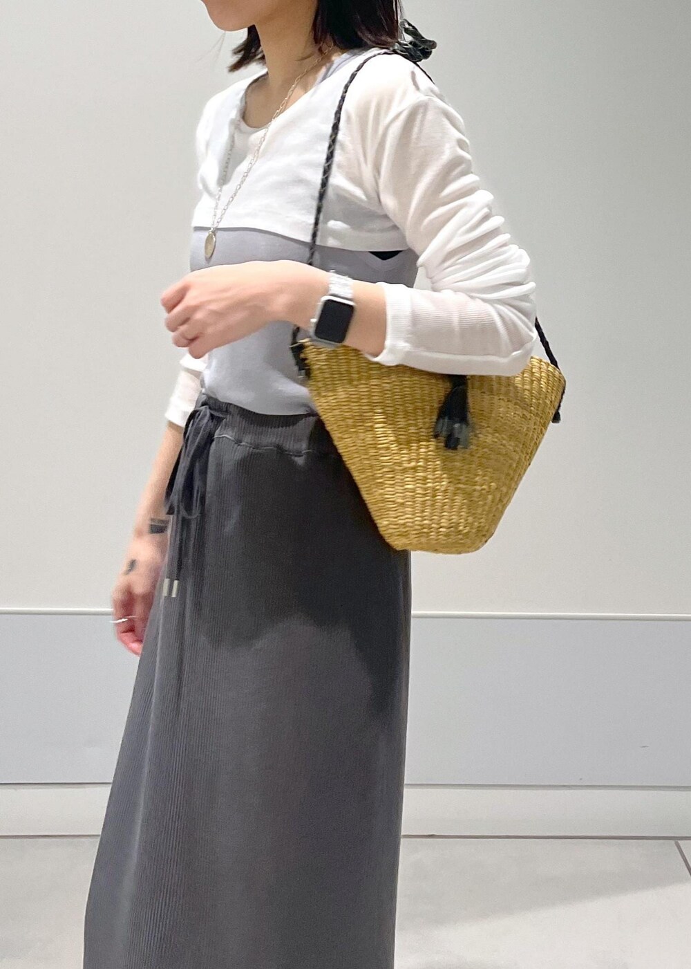 ベージュ系のかごバッグ、グレー系のスカート、グレー系のタンクトップを着用したレディースの夏コーディネートの4枚目の写真