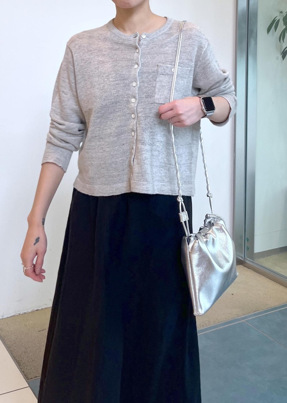 グレー系のカーディガン/ボレロ、ブラック系のスカート、シルバー系のショルダーバッグを着用したレディースの春コーディネートの6枚目の写真