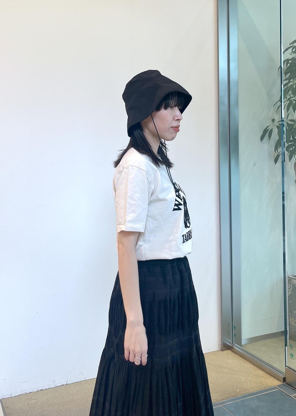 ブラック系のサンダル、ホワイト系のTシャツ/カットソー、ブラック系のスカートを着用したレディースの夏コーディネートの5枚目の写真