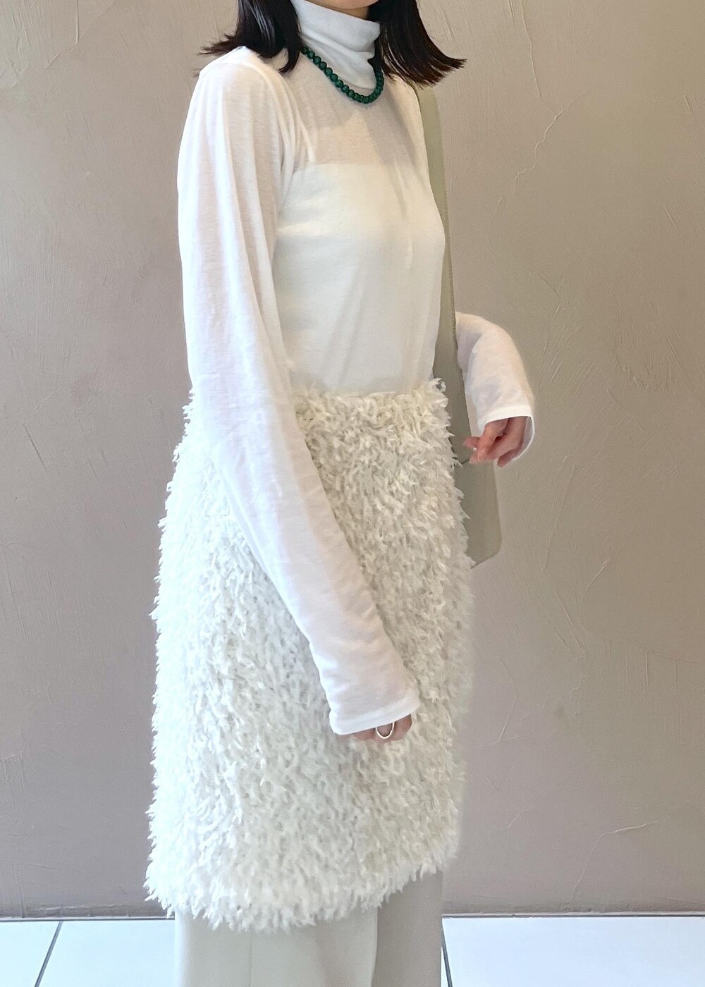 グレー系のショルダーバッグ、ホワイト系のスカート、ベージュ系のその他パンツを着用したレディースの秋コーディネートの7枚目の写真