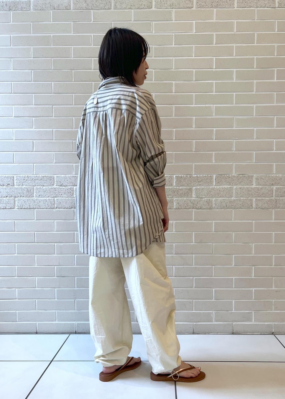 ホワイト系のカーゴパンツ、ブラウン系のサンダル、ホワイト系のチューブトップを着用したレディースの夏コーディネートの2枚目の写真