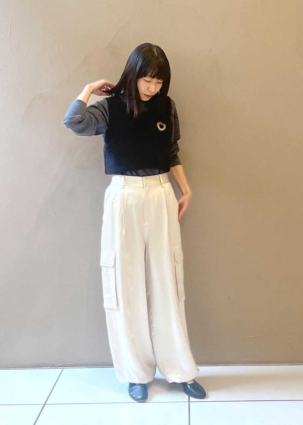 ホワイト系のカーゴパンツ、ブラック系のタンクトップ、グレー系のニット/セーターを着用したレディースの秋コーディネートの2枚目の写真