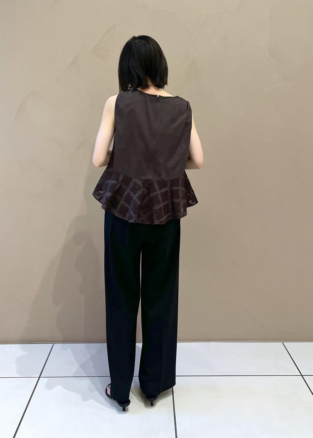 ブラック系のスラックス、シルバー系のサンダルを着用したレディースの夏コーディネートの3枚目の写真