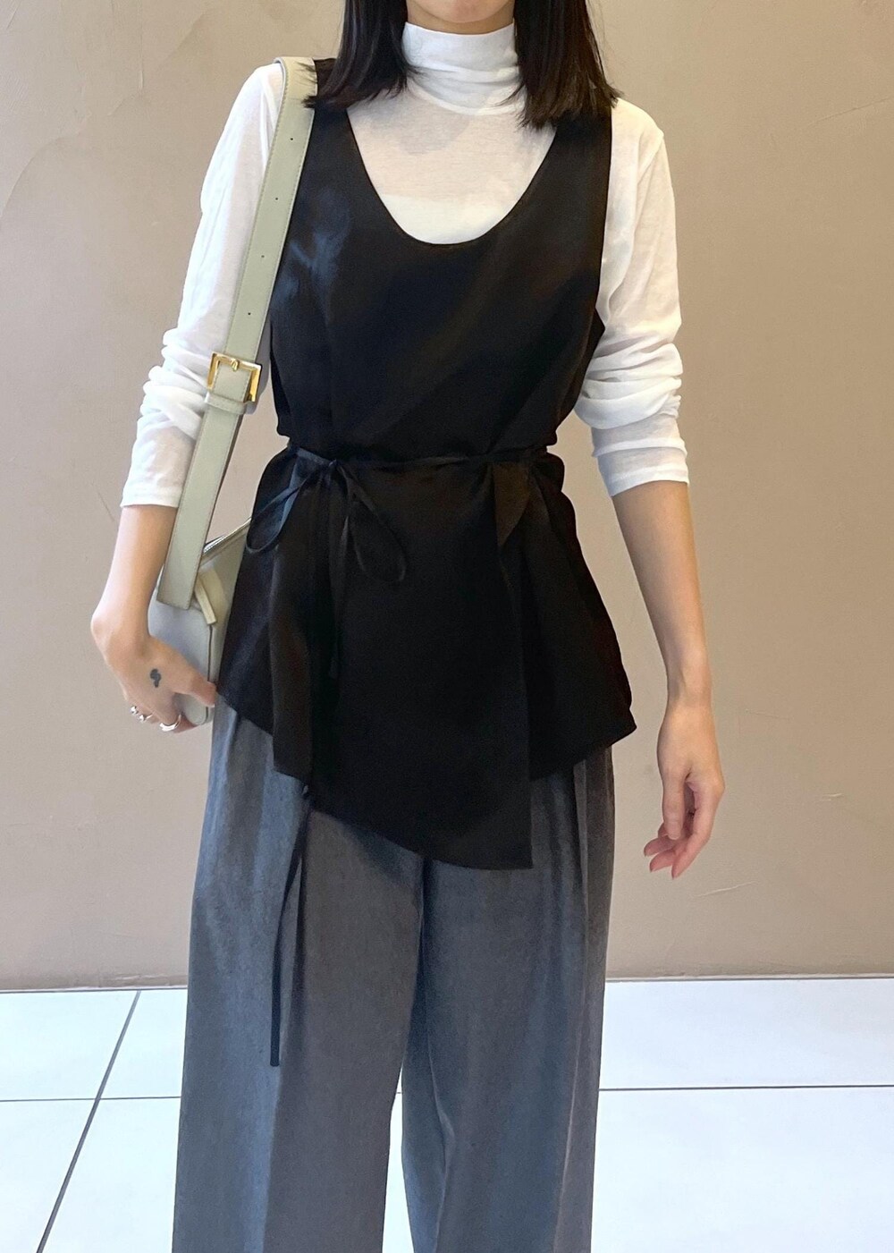 グレー系のショルダーバッグ、ブラック系のTシャツ/カットソー、グレー系のスラックスを着用したレディースの秋コーディネートの6枚目の写真