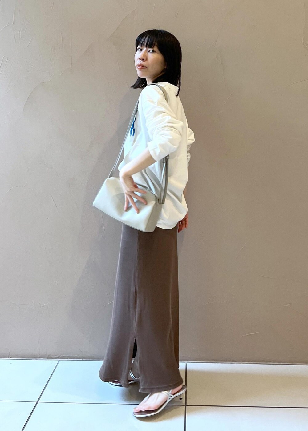 シルバー系のサンダル、ブラウン系のスカート、グレー系のショルダーバッグを着用したレディースの夏コーディネートの3枚目の写真