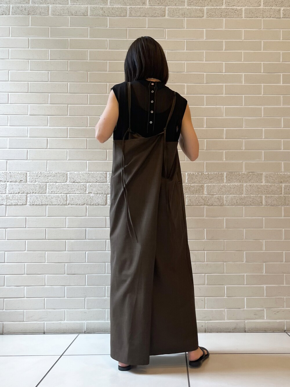 ブラウン系のワンピース、ブラック系のTシャツ/カットソー、ブラック系のサンダルを着用したレディースの夏コーディネートの2枚目の写真