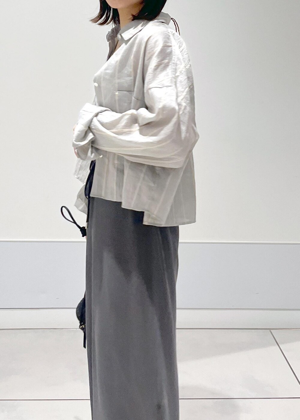 ブラック系のショルダーバッグ、グレー系のスカート、グレー系のタンクトップを着用したレディースの夏コーディネートの5枚目の写真