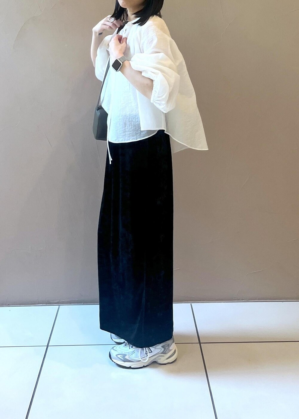 ブラック系のスカート、グリーン系のショルダーバッグ、ホワイト系のシャツ/ブラウスを着用したレディースの夏コーディネートの2枚目の写真