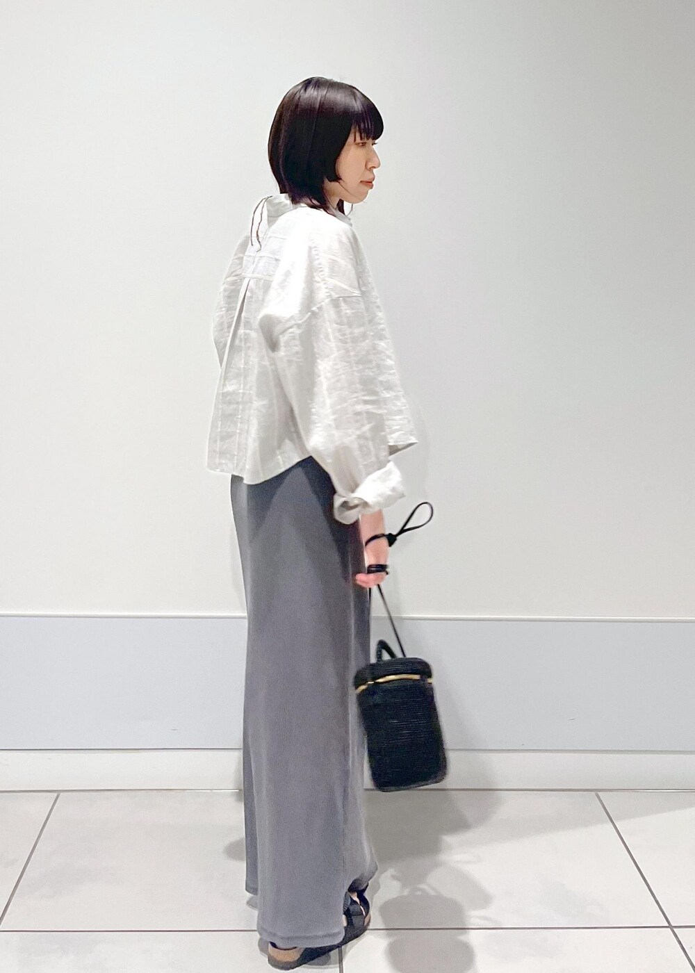 ブラック系のショルダーバッグ、グレー系のスカート、グレー系のタンクトップを着用したレディースの夏コーディネートの2枚目の写真