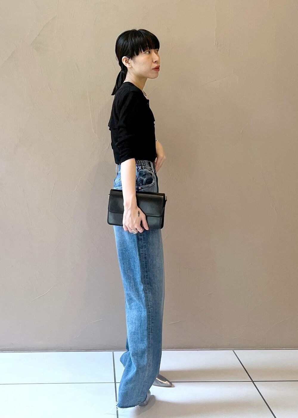 ブルー系のデニムパンツ、ブラック系のショルダーバッグ、ブラック系のカーディガン/ボレロを着用したレディースの夏コーディネートの2枚目の写真