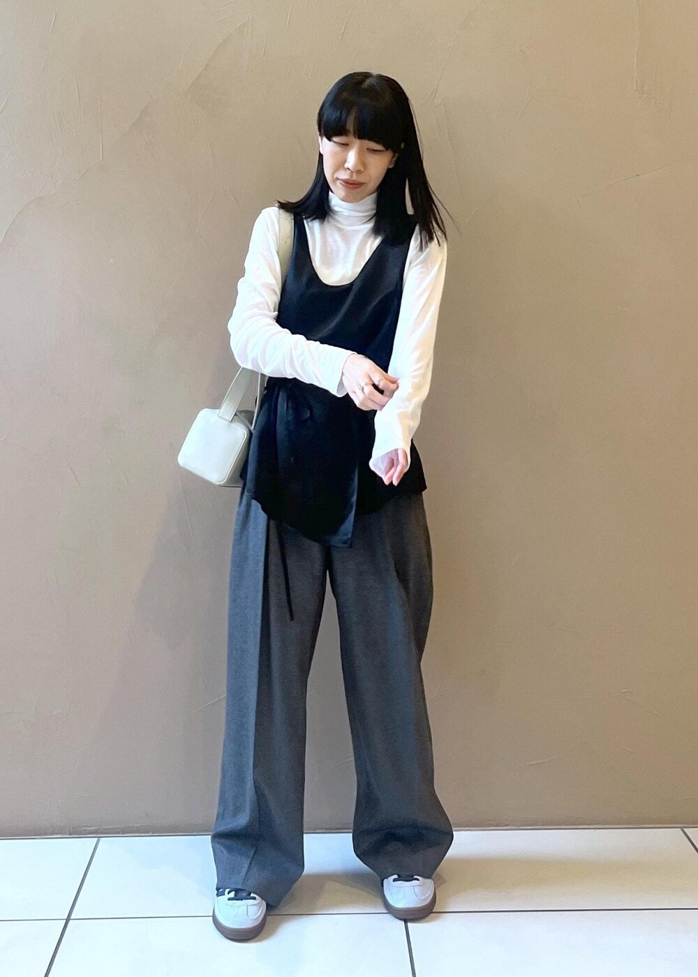 グレー系のショルダーバッグ、ブラック系のTシャツ/カットソー、グレー系のスラックスを着用したレディースの秋コーディネートの5枚目の写真