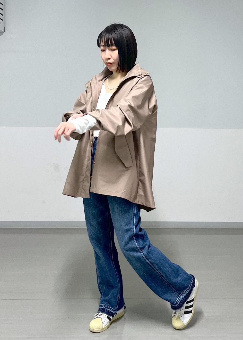 ブラウン系のマウンテンパーカー、グレー系のスカート、ブルー系のデニムパンツを着用したレディースの冬コーディネートの7枚目の写真