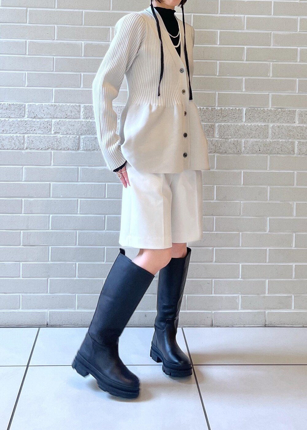 ブラック系のブーツ、ホワイト系のその他パンツ、グレー系のカーディガン/ボレロを着用したレディースの秋コーディネートの5枚目の写真