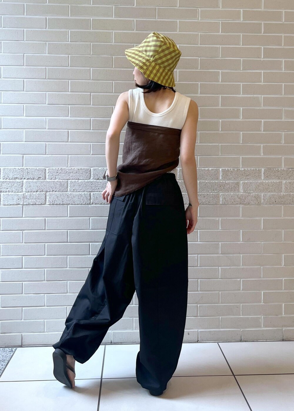 ホワイト系のタンクトップ、ブラック系のサンダル、ブラック系のカーゴパンツを着用したレディースの夏コーディネートの3枚目の写真