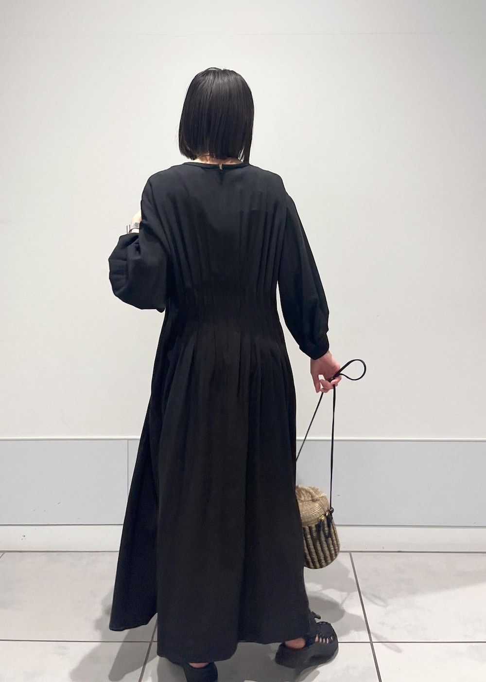 ブラック系のワンピース、ブラック系のサンダル、ホワイト系のショルダーバッグを着用したレディースの春コーディネートの2枚目の写真