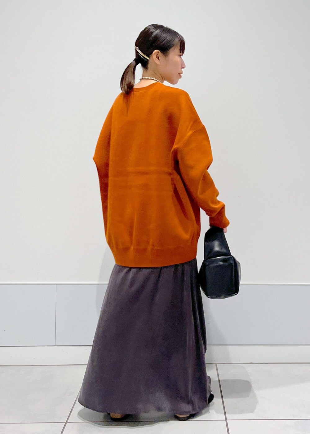 ブラック系のハンドバッグ、ブラック系のサンダル、レッド系のスウェットを着用したレディースの夏コーディネートの3枚目の写真