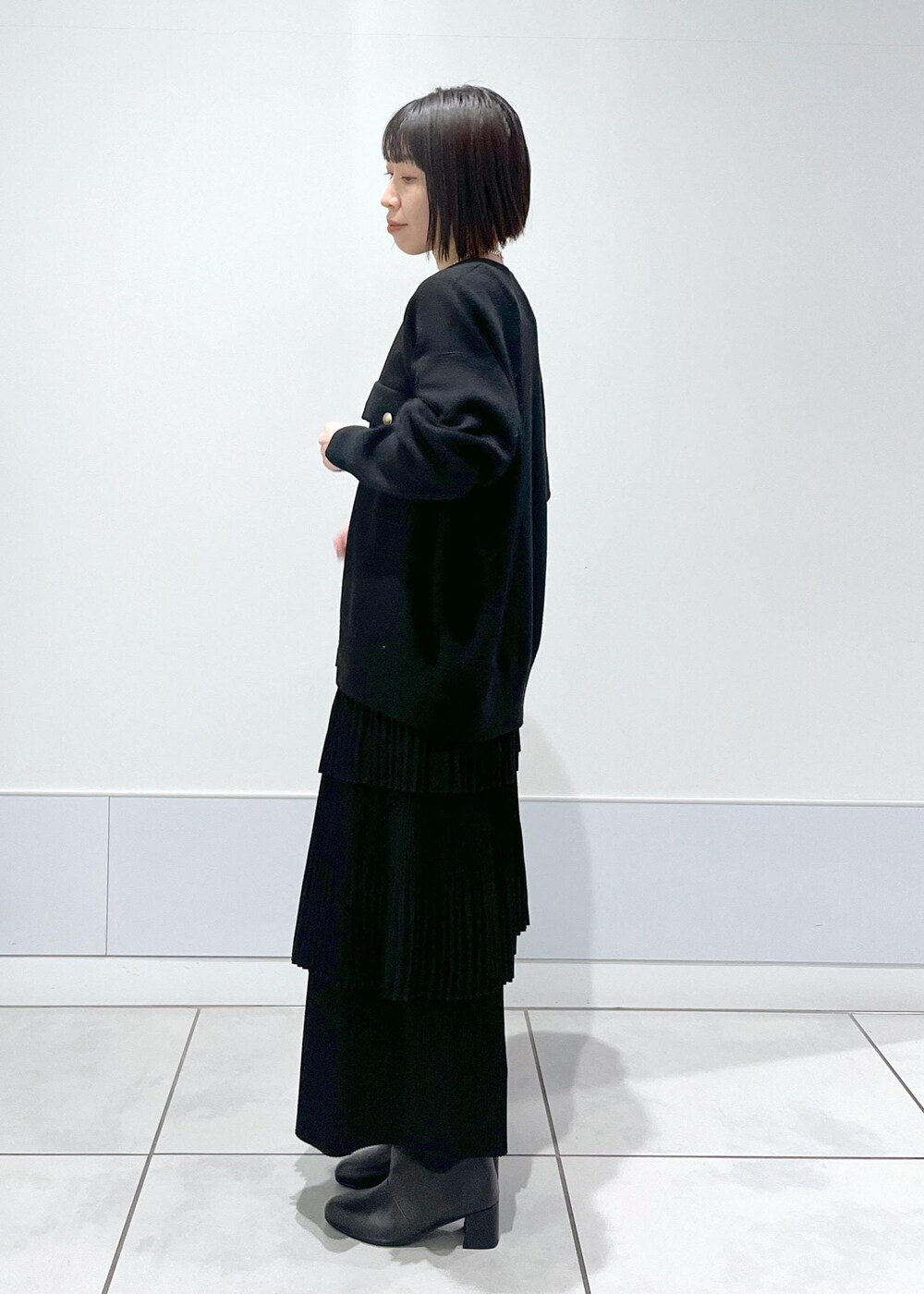 ブラック系のブーツ、ブラック系のカーディガン/ボレロ、ブラック系のスカートを着用したレディースの冬コーディネートの2枚目の写真