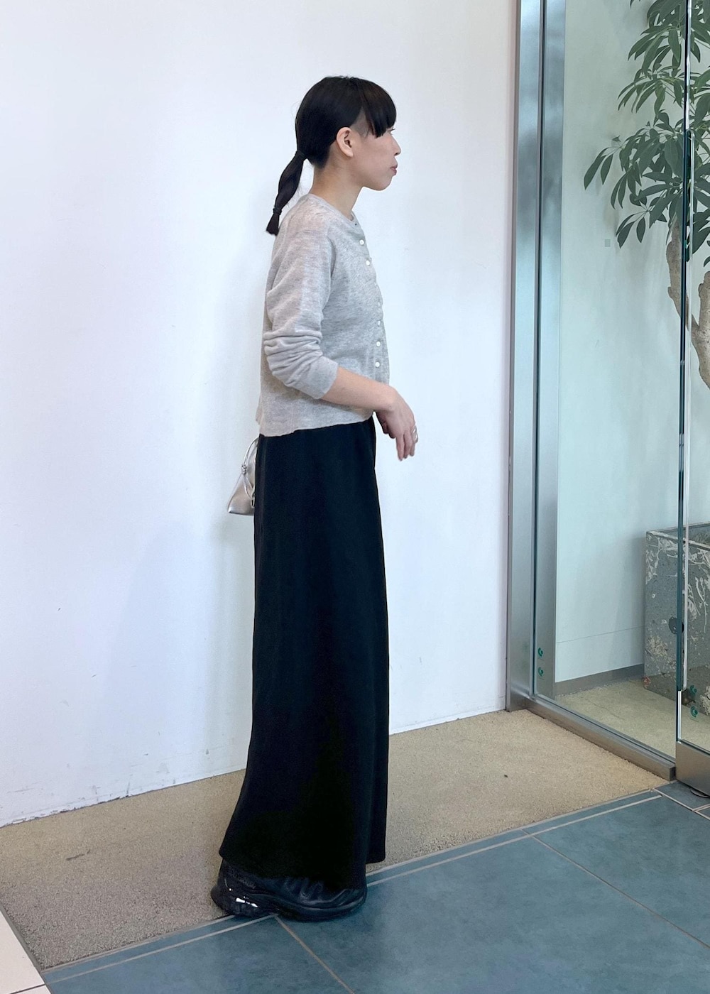 グレー系のカーディガン/ボレロ、ブラック系のスカート、シルバー系のショルダーバッグを着用したレディースの春コーディネートの2枚目の写真
