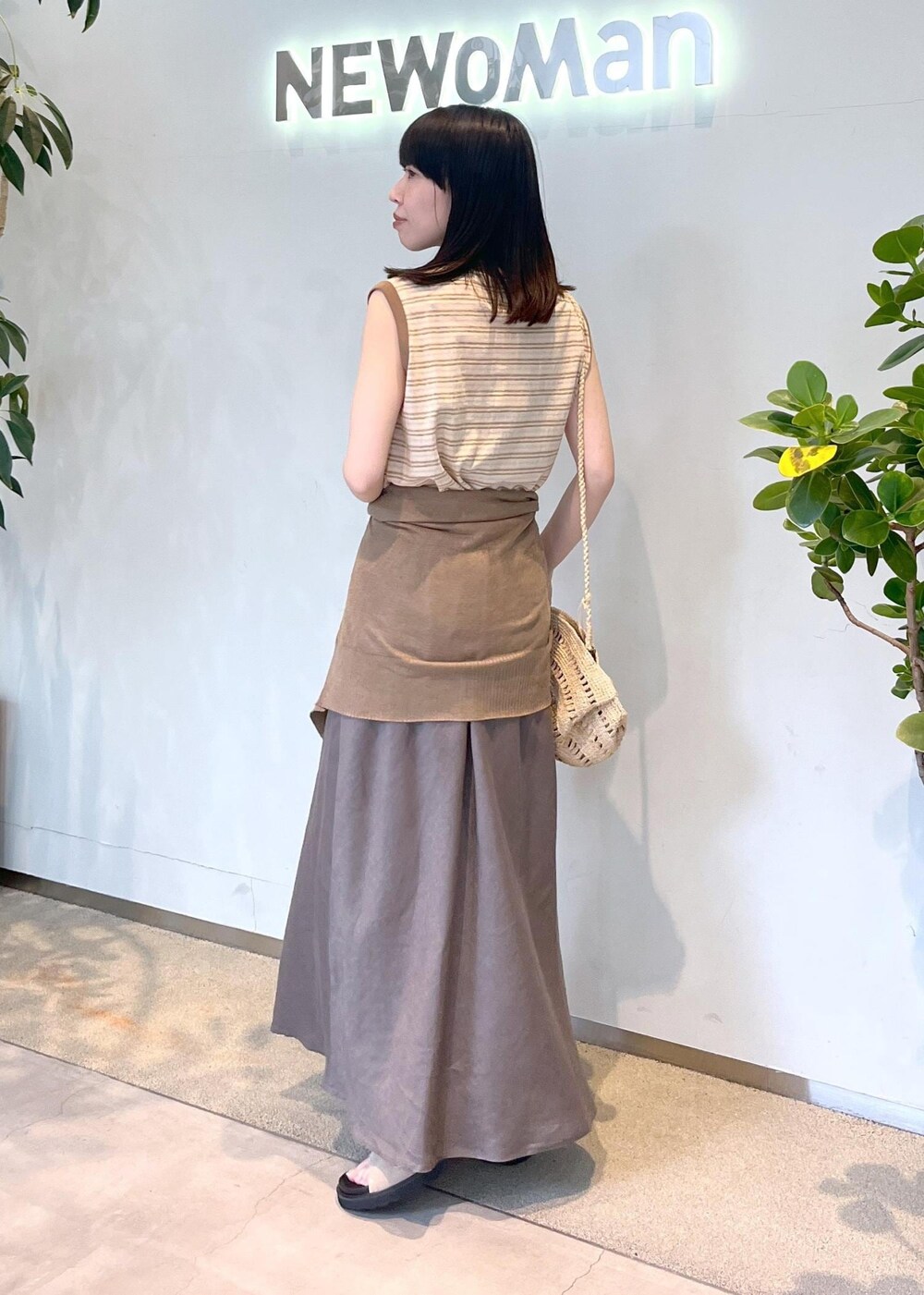 ベージュ系のサンダル、グレー系のスカート、ゴールド系のカーディガン/ボレロを着用したレディースの春コーディネートの2枚目の写真