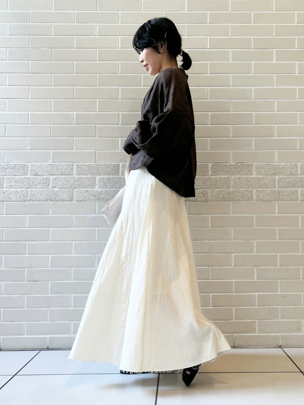 ブラウン系のシャツ/ブラウス、ベージュ系のハンドバッグ、ホワイト系のスカートを着用したレディースの春コーディネートの2枚目の写真