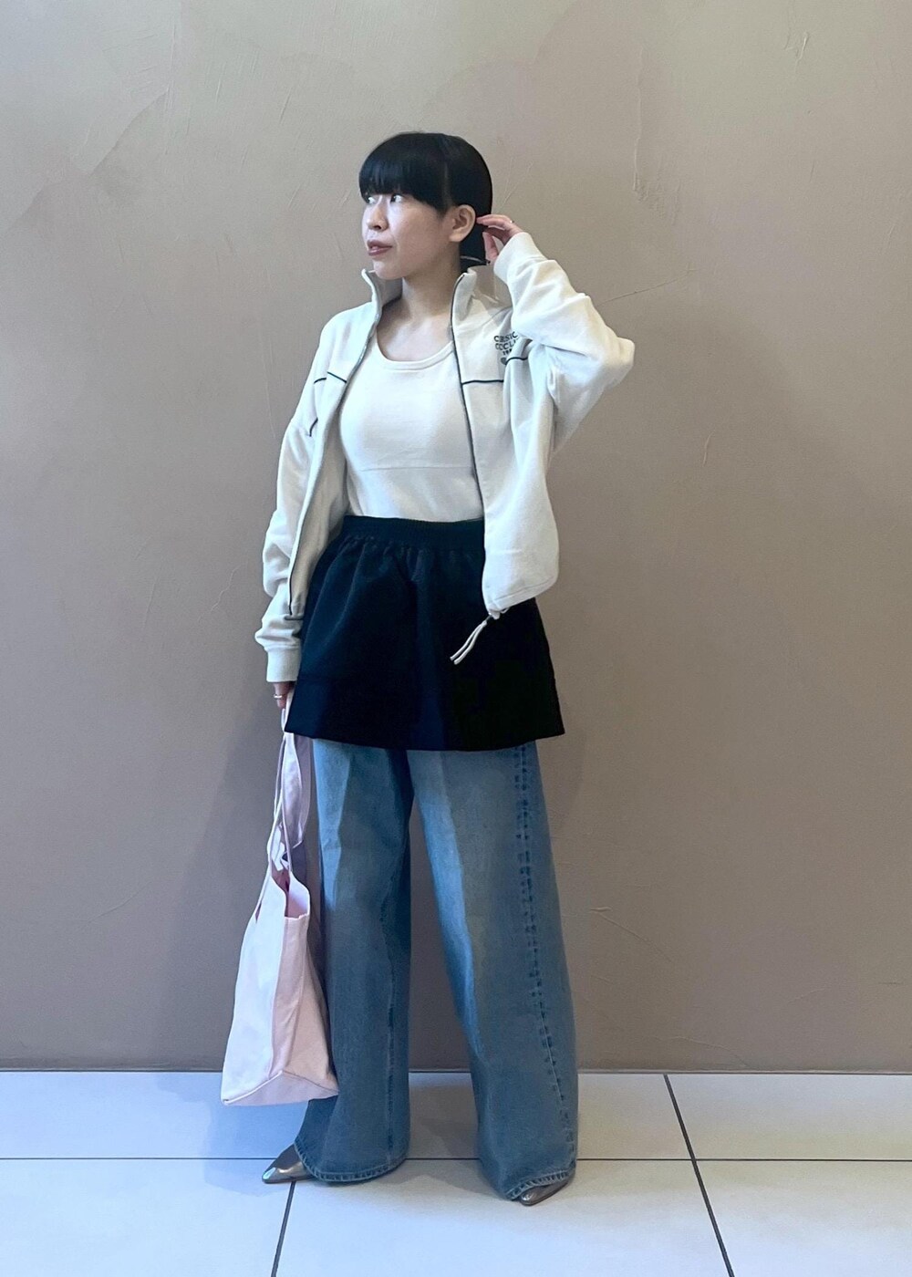 ブルー系のデニムパンツ、ブラック系のスカート、ホワイト系のタンクトップを着用したレディースの冬コーディネートの2枚目の写真