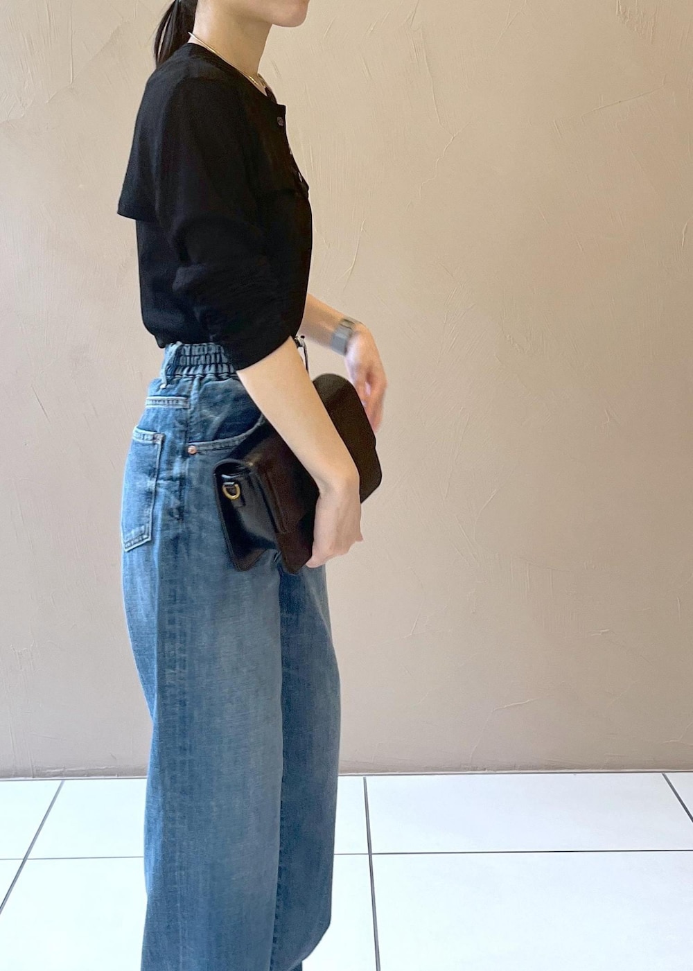 ブルー系のデニムパンツ、ブラック系のショルダーバッグ、ブラック系のカーディガン/ボレロを着用したレディースの夏コーディネートの5枚目の写真