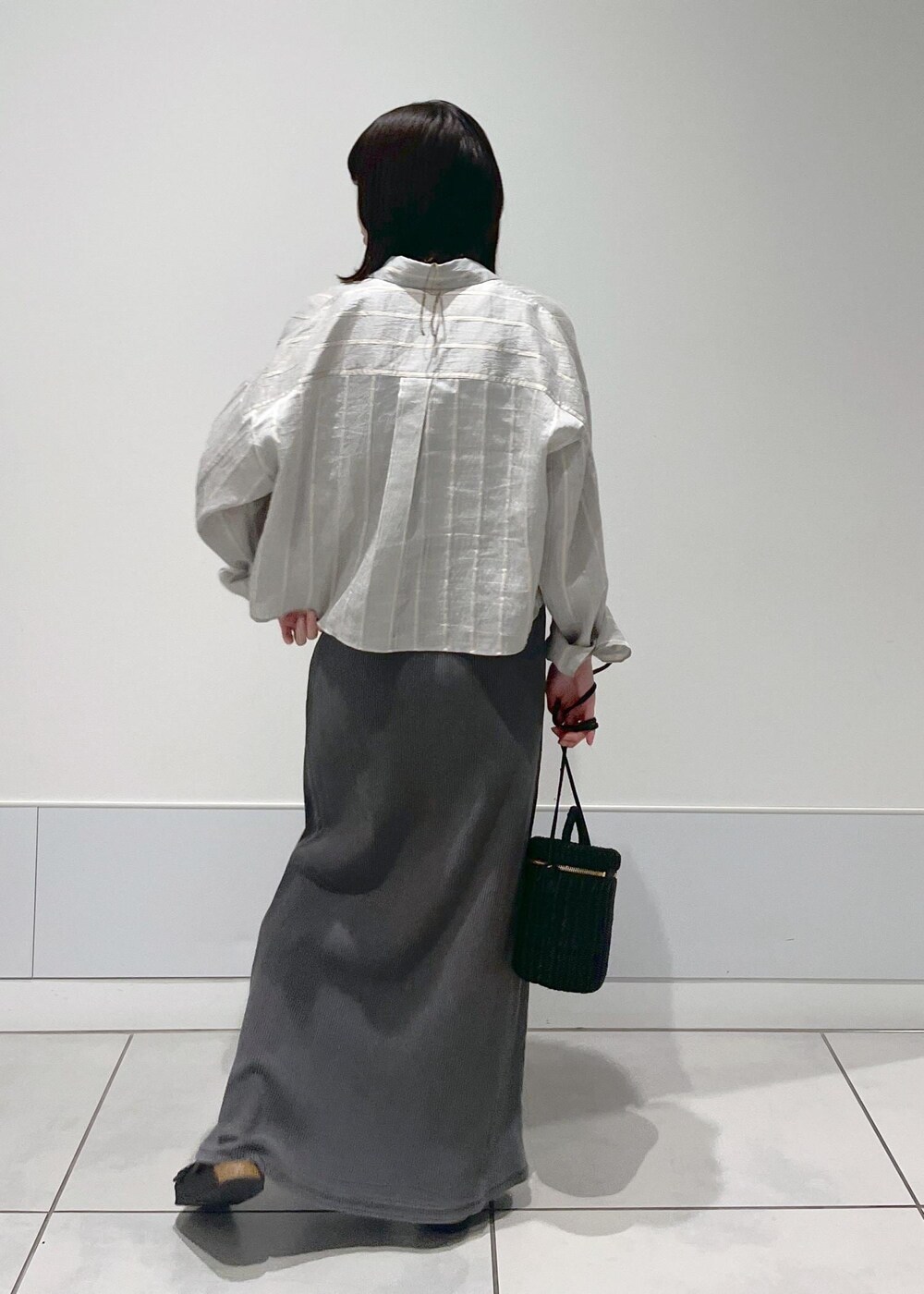 ブラック系のショルダーバッグ、グレー系のスカート、グレー系のタンクトップを着用したレディースの夏コーディネートの3枚目の写真