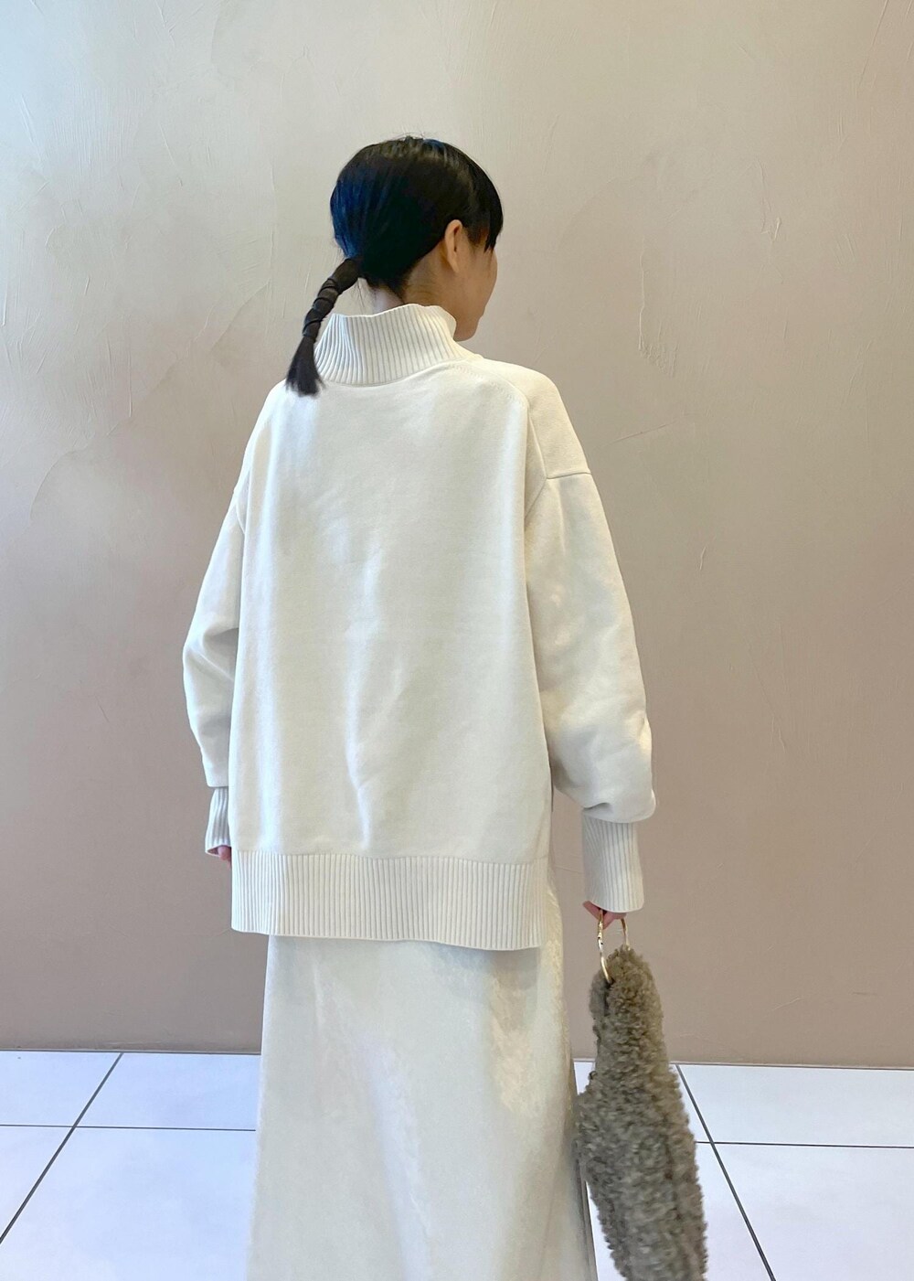ホワイト系のスカート、ホワイト系のニット/セーター、ブラウン系のハンドバッグを着用したレディースの秋コーディネートの7枚目の写真