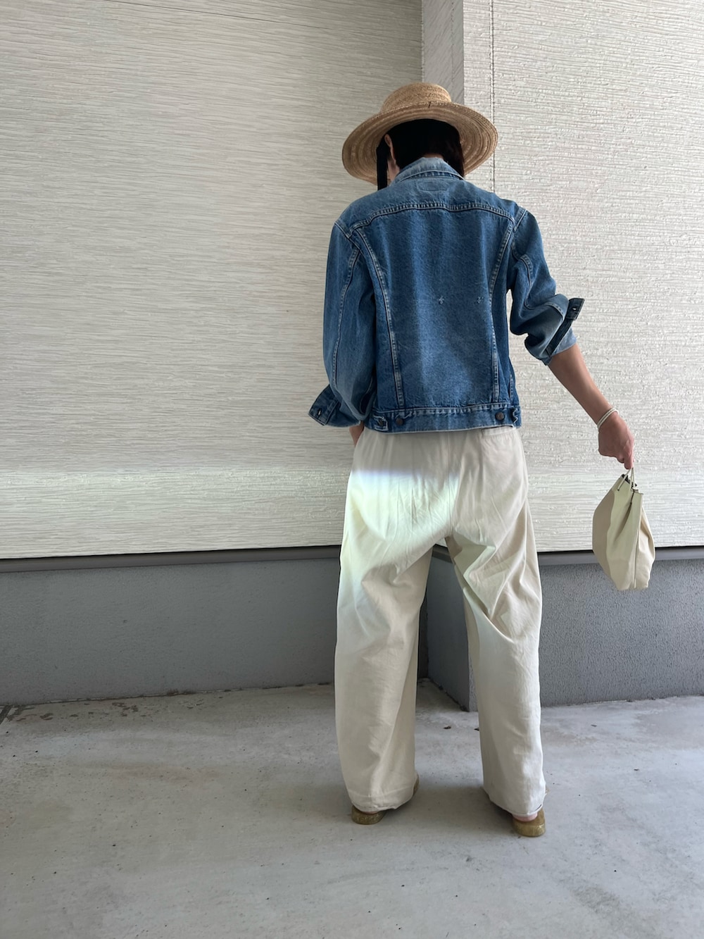 ホワイト系のハンドバッグ、ベージュ系のチノパンツ、ベージュ系のタンクトップを着用したレディースの春コーディネートの3枚目の写真