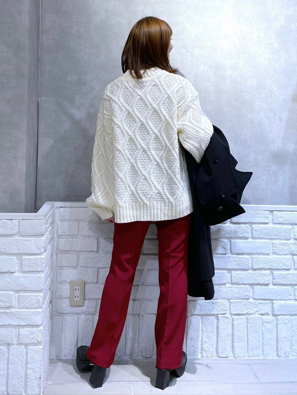 ブラック系のトレンチコート、シルバー系のボストンバッグ、レッド系のスラックスを着用したレディースの冬コーディネートの2枚目の写真