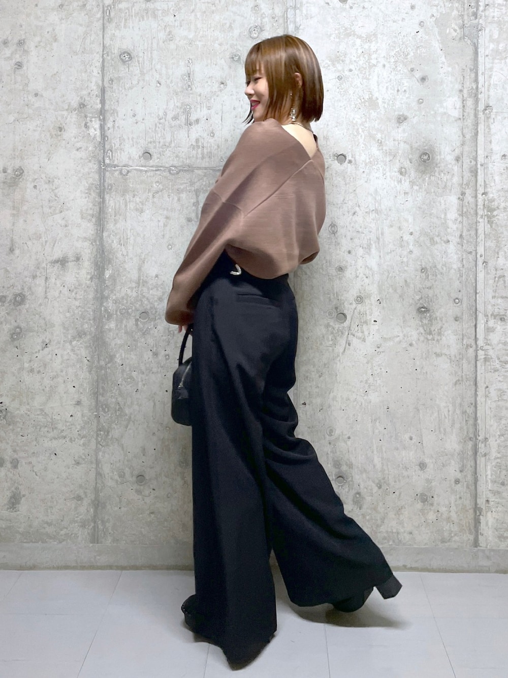 ブラウン系のニット/セーター、ブラック系のボストンバッグ、ブラック系のスラックスを着用したレディースの冬コーディネートの3枚目の写真