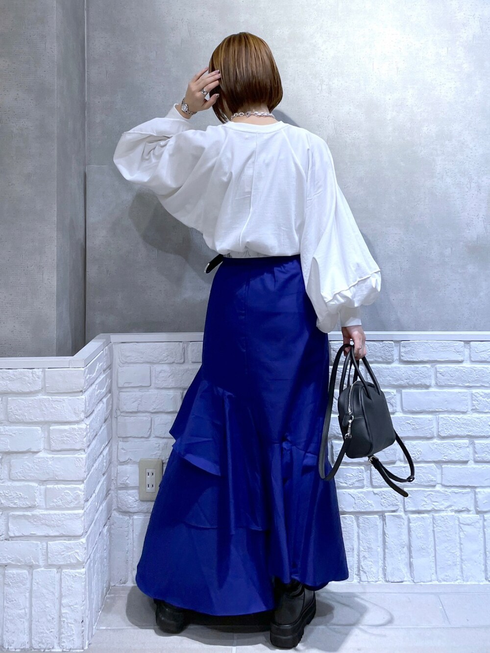 ホワイト系のTシャツ/カットソー、ブラック系のボストンバッグ、ブルー系のスカートを着用したレディースの冬コーディネートの2枚目の写真