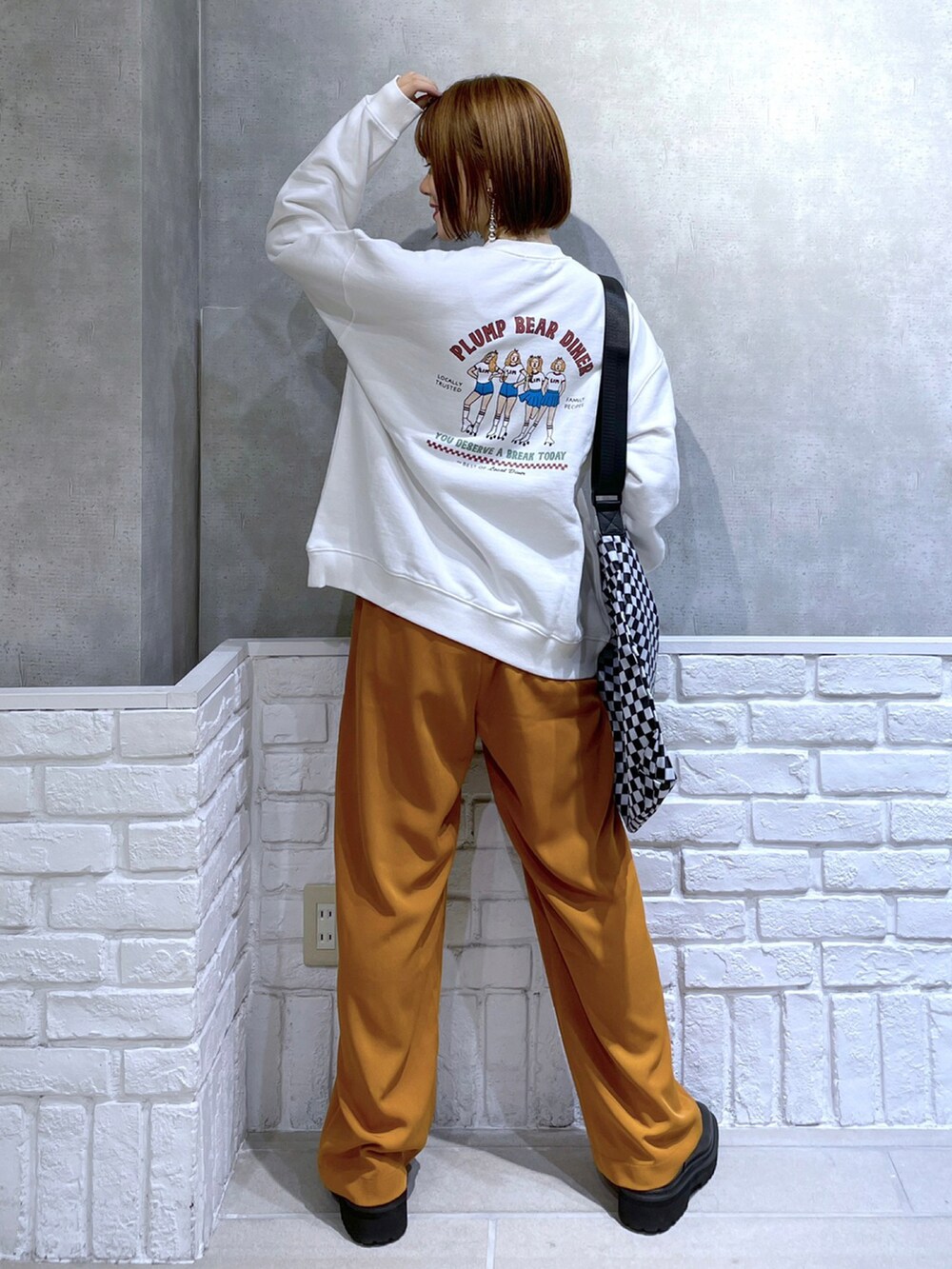 ホワイト系のスウェット、ブラック系のショルダーバッグ、オレンジ系のその他パンツを着用したレディースの冬コーディネートの2枚目の写真