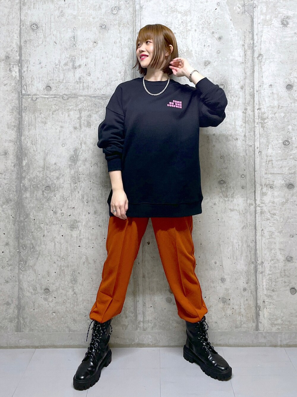 オレンジ系のスラックス、ブラック系のブーツ、ブラック系のスウェットを着用したレディースの冬コーディネートの3枚目の写真