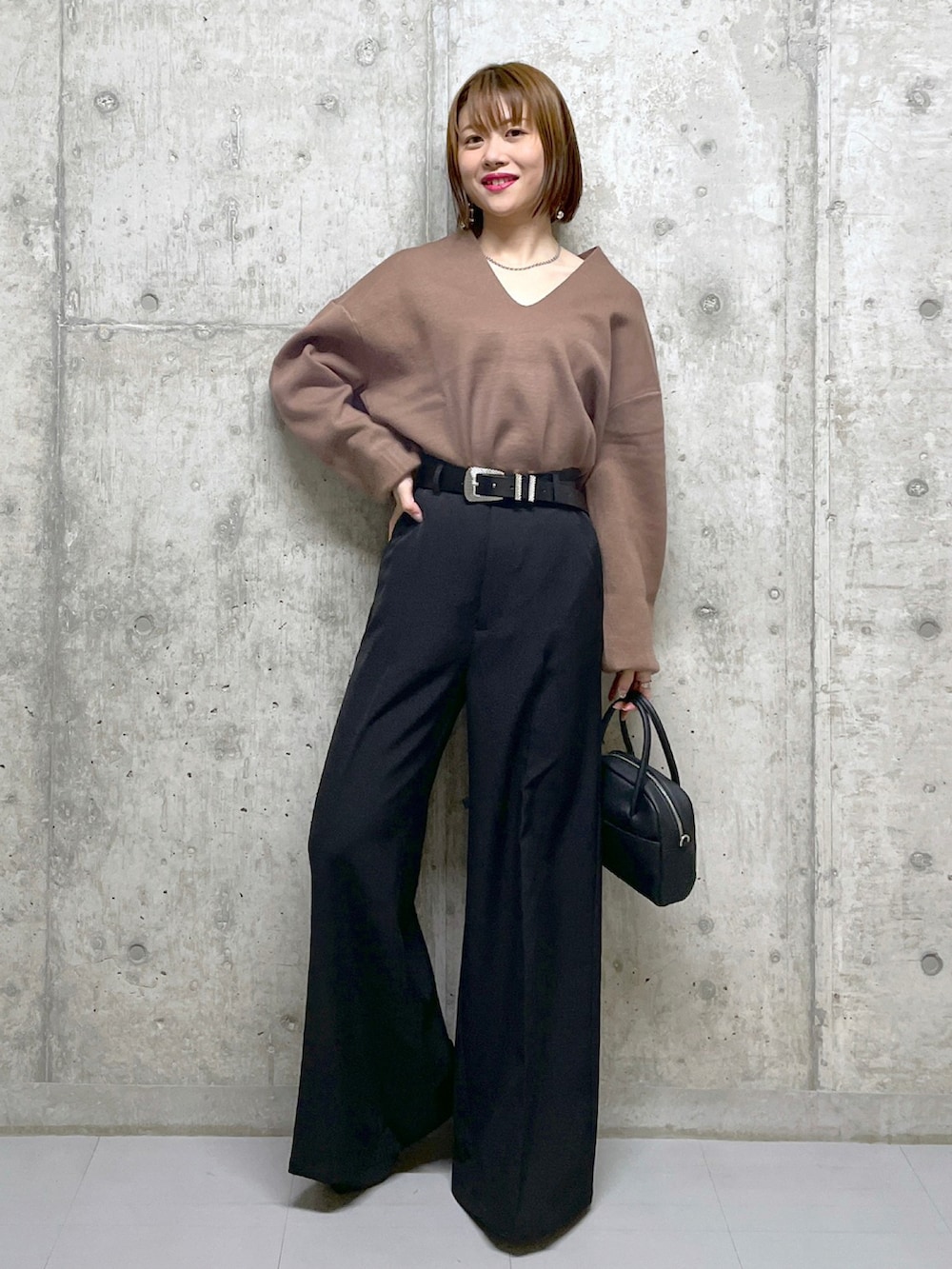 ブラウン系のニット/セーター、ブラック系のボストンバッグ、ブラック系のスラックスを着用したレディースの冬コーディネートの2枚目の写真