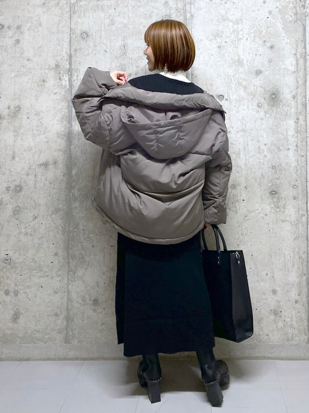 ブラウン系のブルゾン、ブラック系のワンピース、ブラック系のトートバッグを着用したレディースの冬コーディネートの2枚目の写真