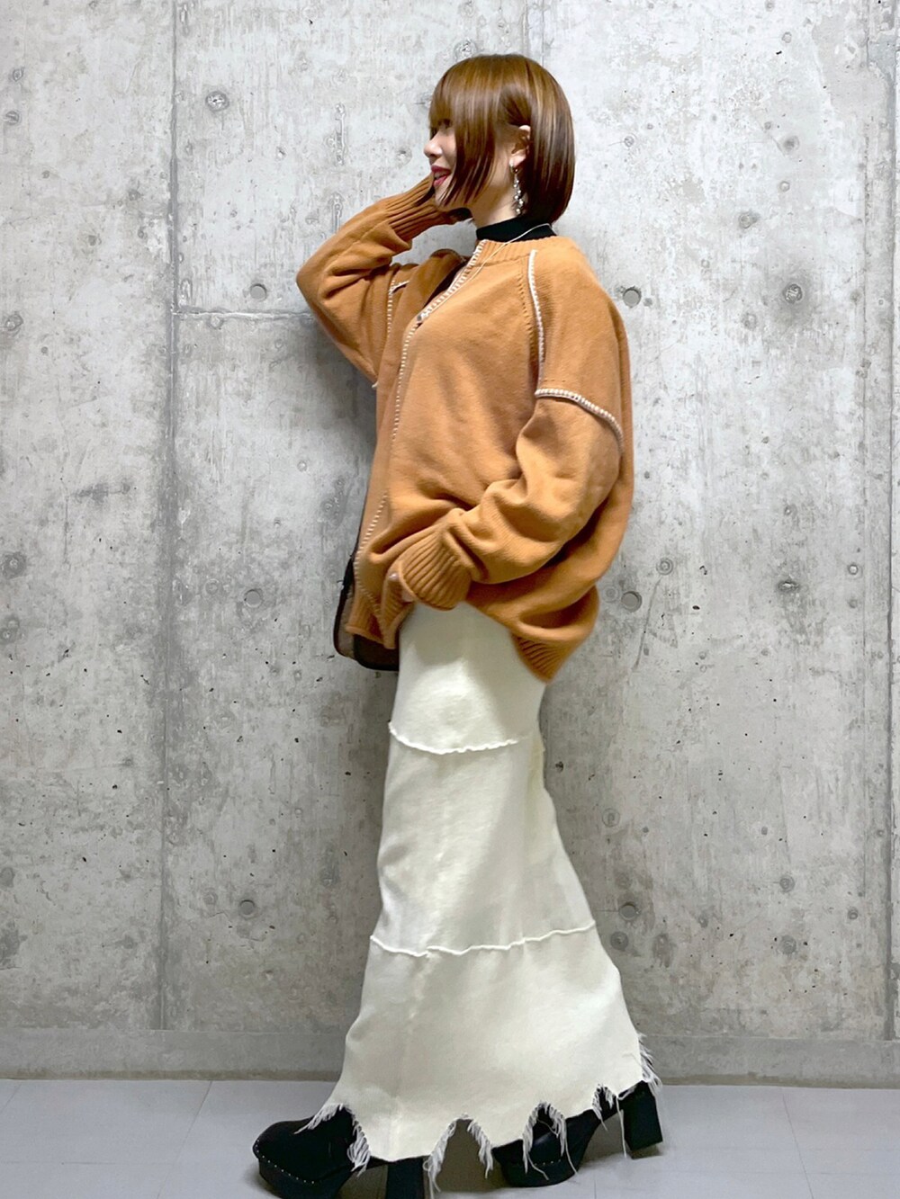 ブラウン系のショルダーバッグ、オレンジ系のニット/セーター、ブラック系のニット/セーターを着用したレディースの冬コーディネートの2枚目の写真